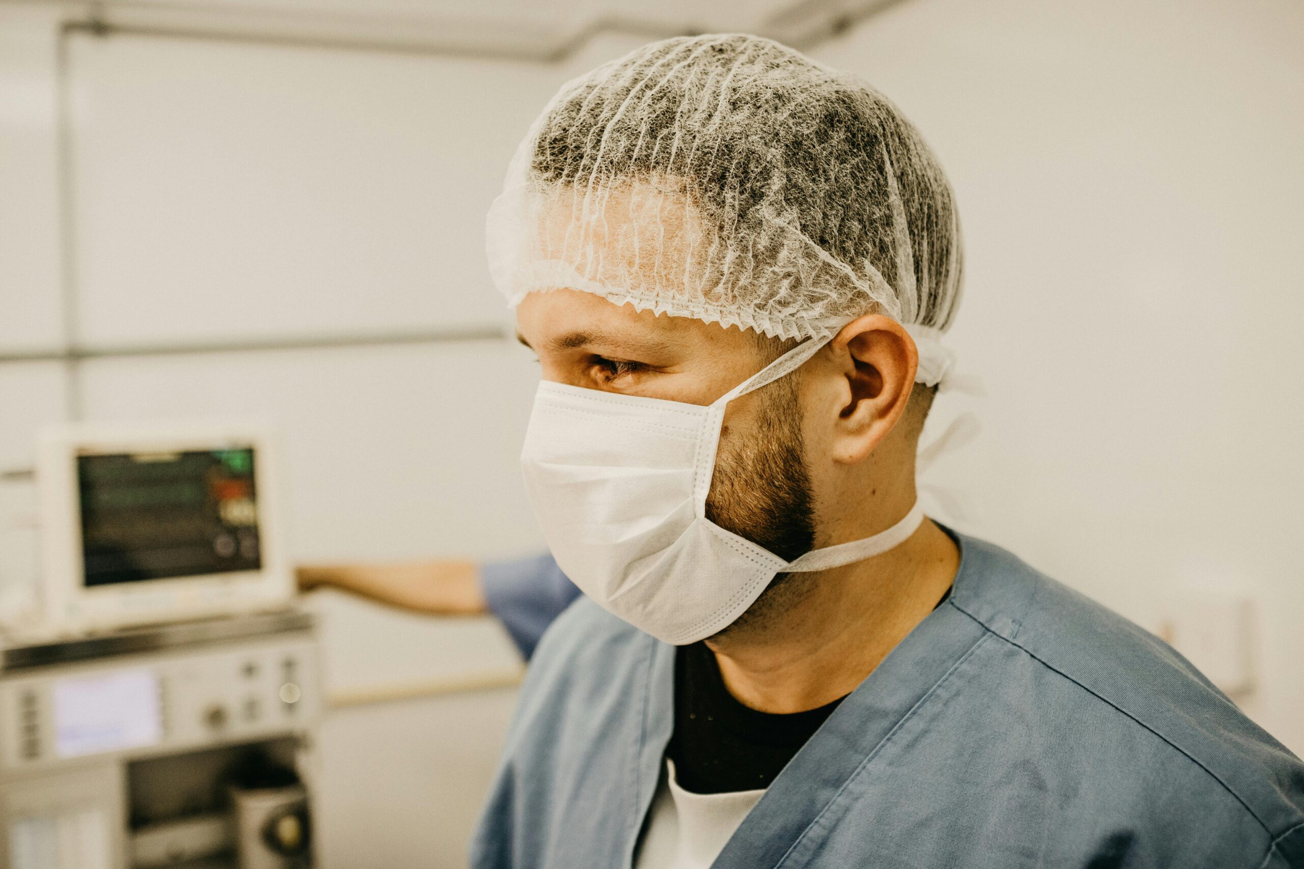 Healthcare professional in hospital setting wearing face mask and hair net.
